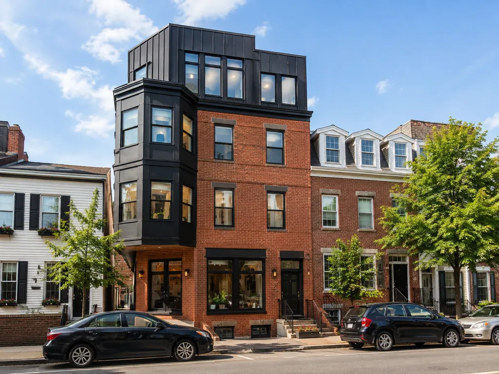 A row of brick buildings with cars parked in front on a sunny day.