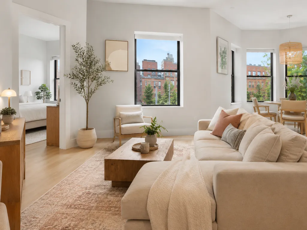 A living room with a white couch, wooden coffee table, and large windows.