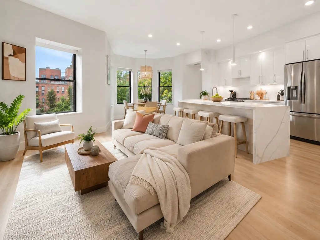 A modern living room with a white couch, wooden coffee table, and a kitchen island.